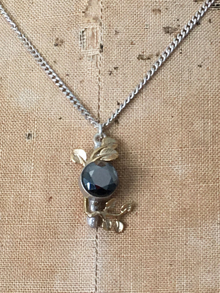 Close up of bud necklace by Lotta, open bud and chain in sterling silver with leaf motifs in brass